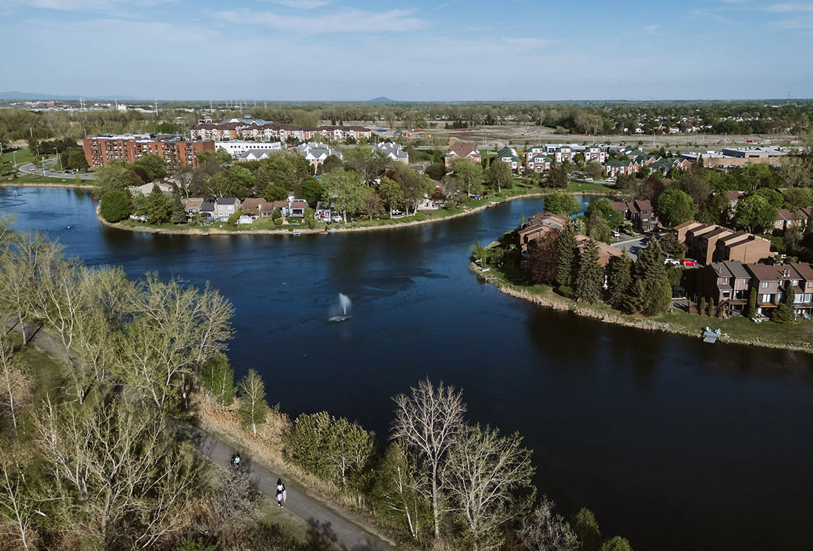 Une vue aérienne de La Prairie montrant le bassin de rétention (lac de la Citière) et le terrain vague qui sera bientôt l'écoquatier TOD La-Prairie-sur-le-Parc.