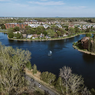 Une vue aérienne de La Prairie montrant le bassin de rétention (lac de la Citière) et le terrain vague qui sera bientôt l'écoquatier TOD La-Prairie-sur-le-Parc.