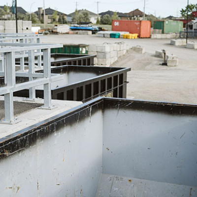 Trois conteneurs sont sur un sol de béton à l'extérieur et la vue mène sur l'intérieur, vide, de l'un d'entre eux.